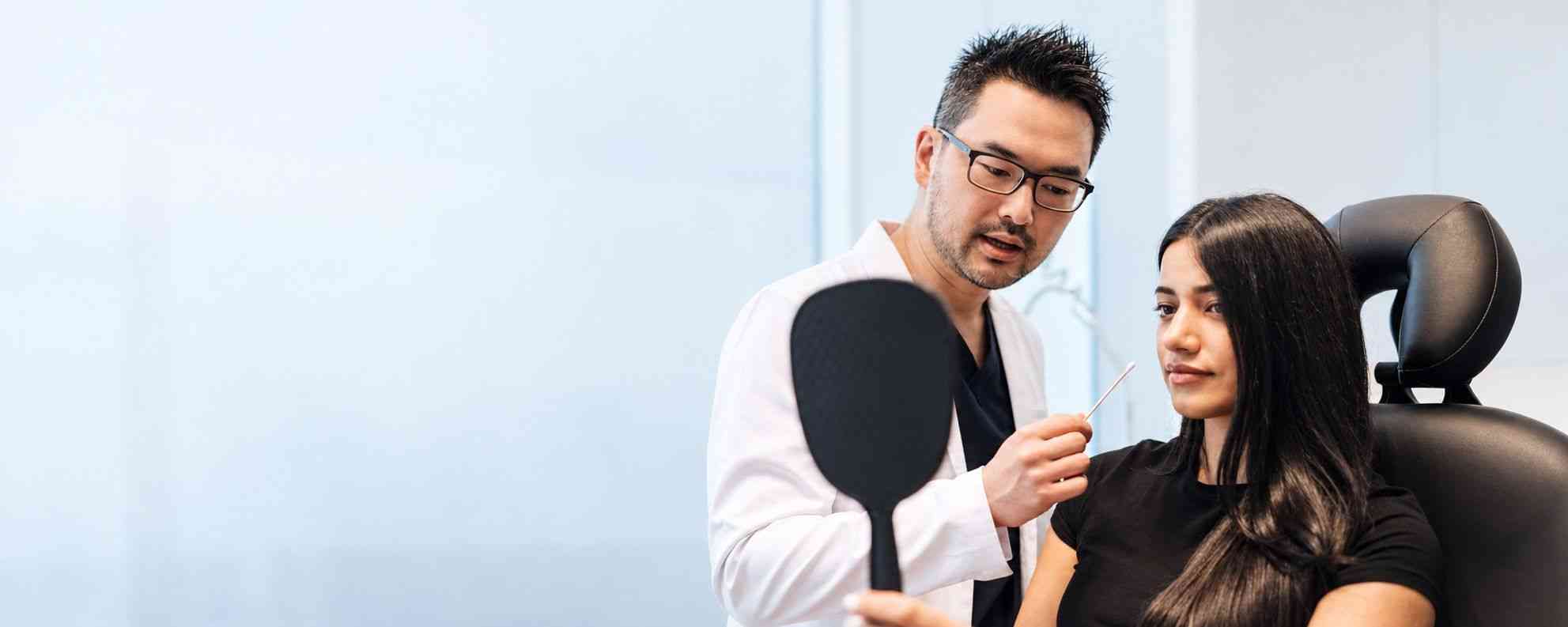Dr. Danny Guo discussing dermal filler treatment with a patient in Calgary